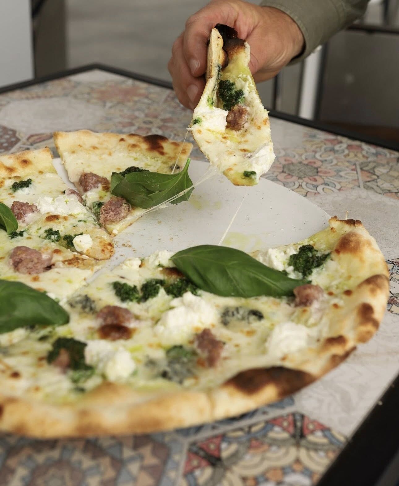 Pizza bianca z serem i bazylią, kawałek unoszony z talerza