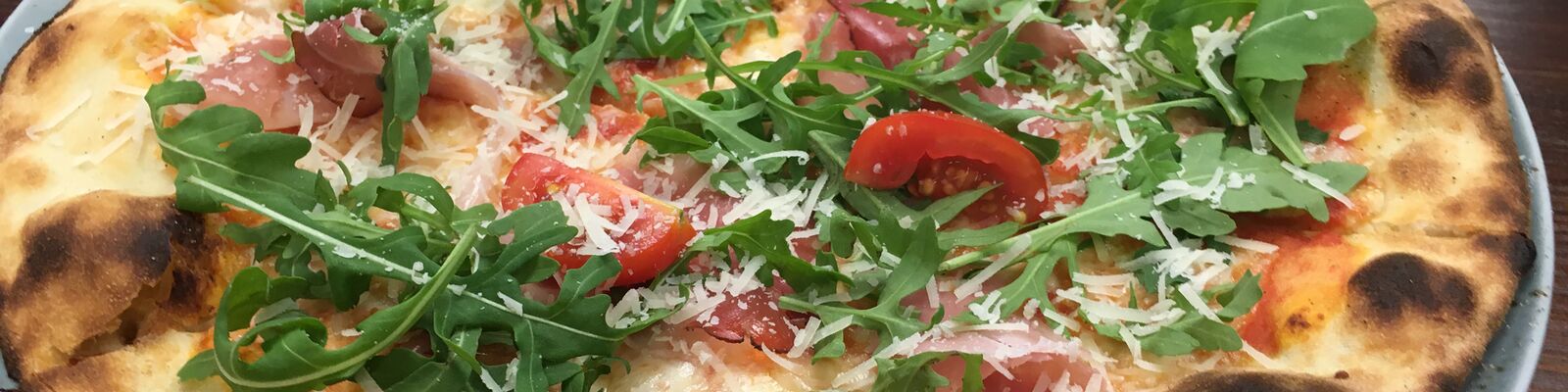 Autorska pizza na cieście proziakowym z rukolą, szynką i pomidorami