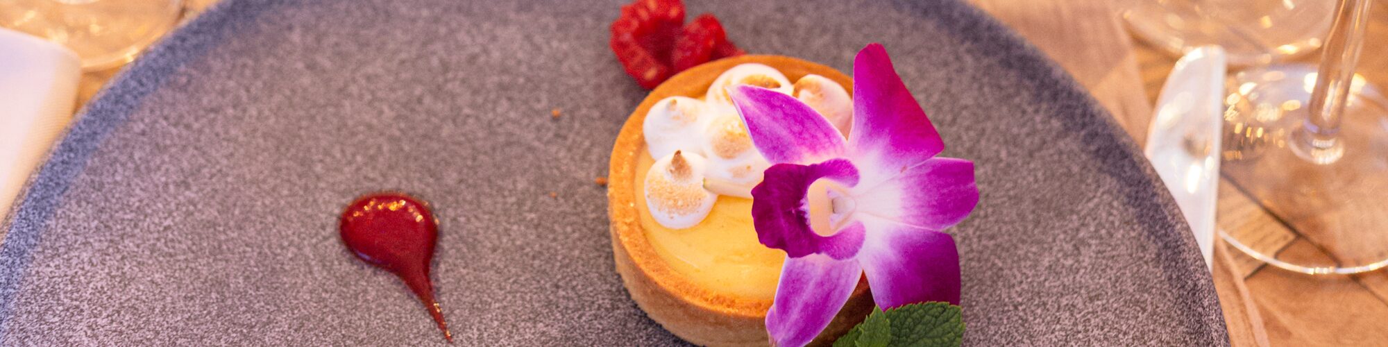 Deser w Pastelove Cafe: tarta z opalaną bezą, maliną i jadalnym kwiatem na kamiennym talerzu